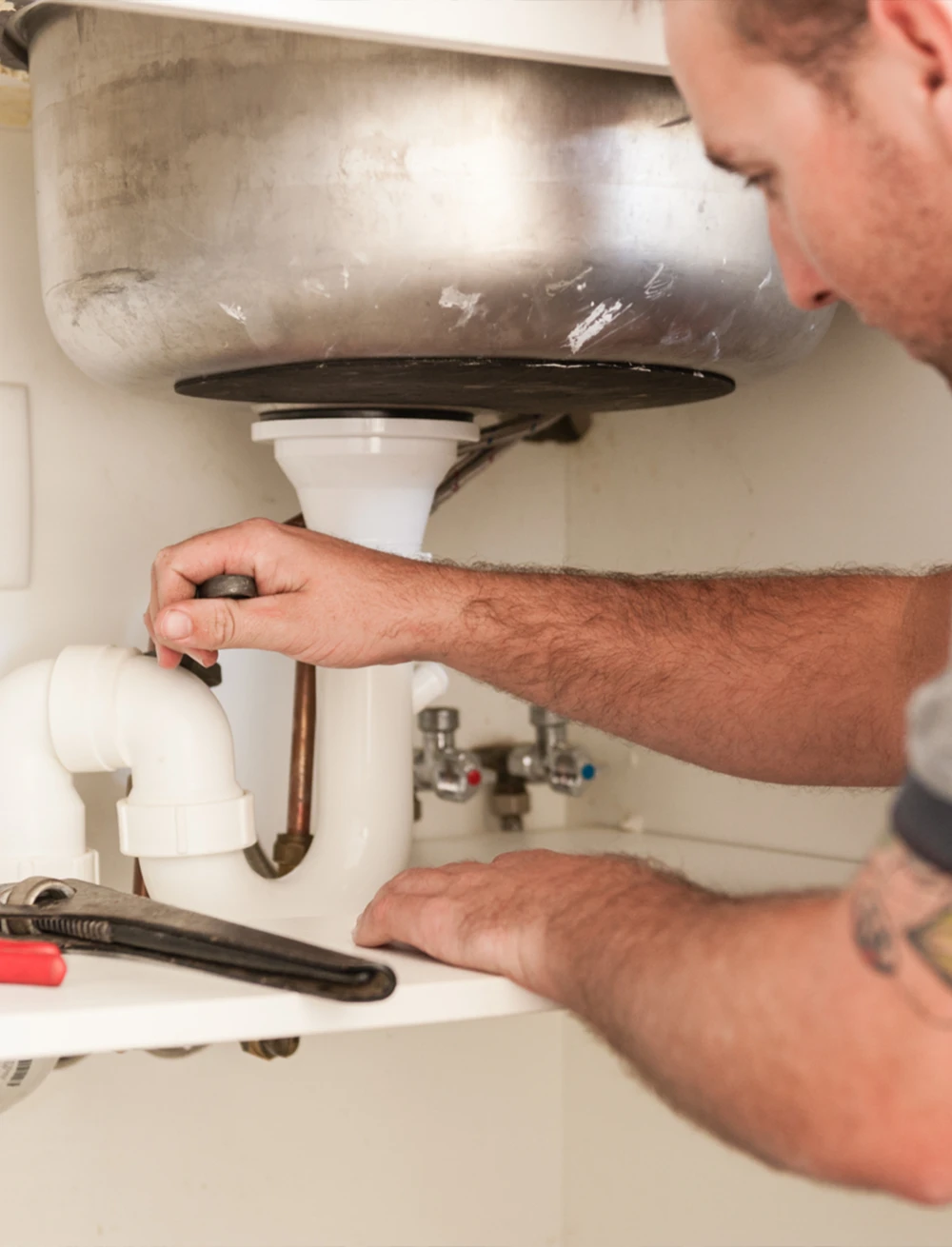 Plumber fixing a pipe under the sink